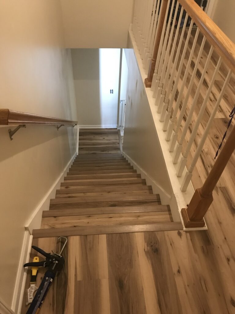 LVP stair installation with wood railing
