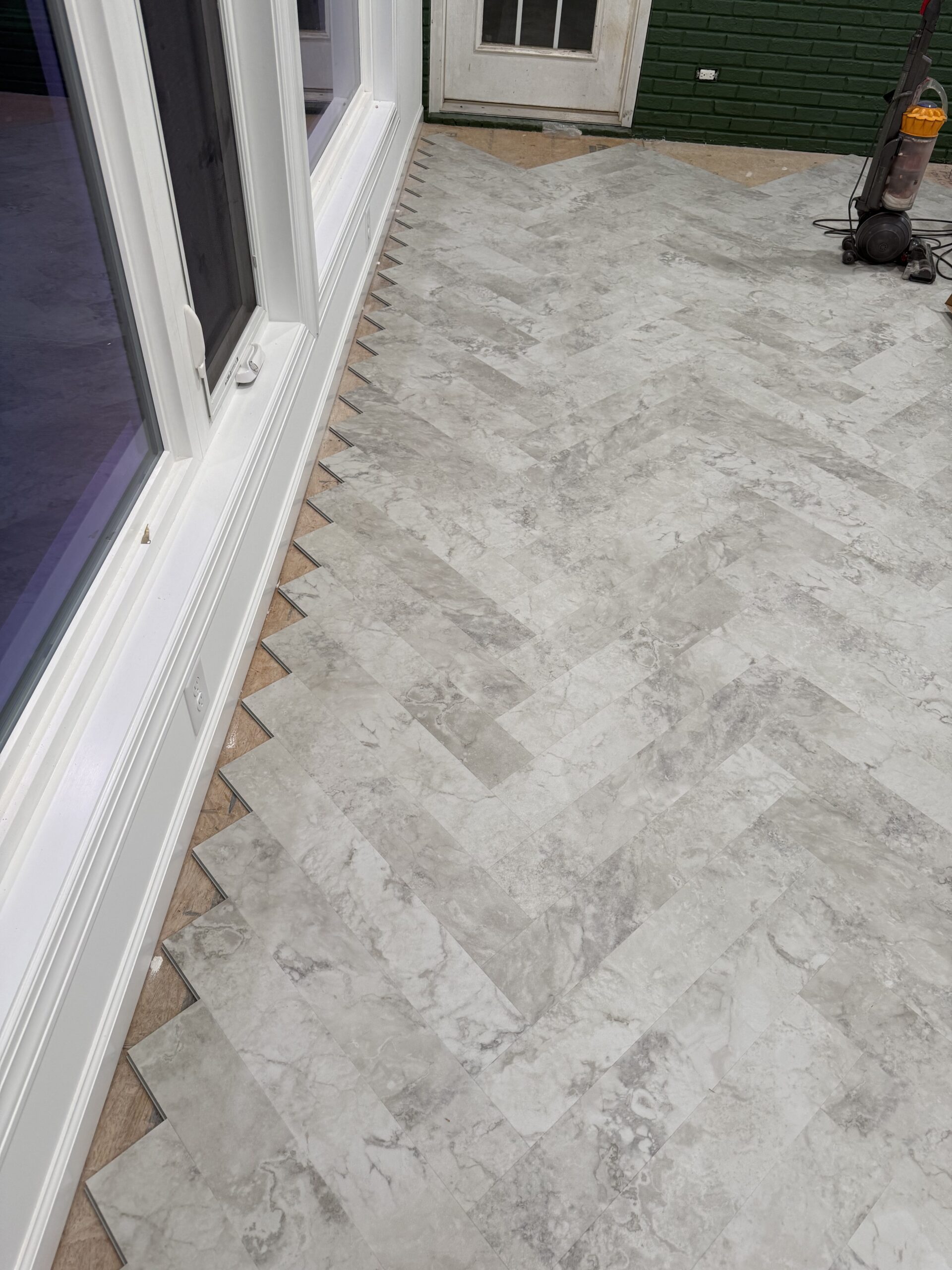 Herringbone pattern with LVP in new construction sunroom.
